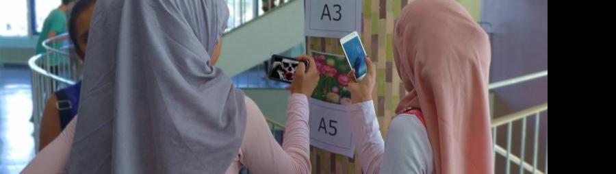schul-stiegenhaus, zwei jugendliche schauen auf smartphone, markierung an der wand